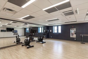 A spacious room with exercise bikes, a large mirror, and a wooden floor. - Landing | Incredible 1BD, Pool (West Hartford)