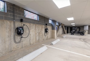 Eine Parkgarage mit Betonwänden, einem Fahrzeug und zwei Ladestationen für Elektroautos.