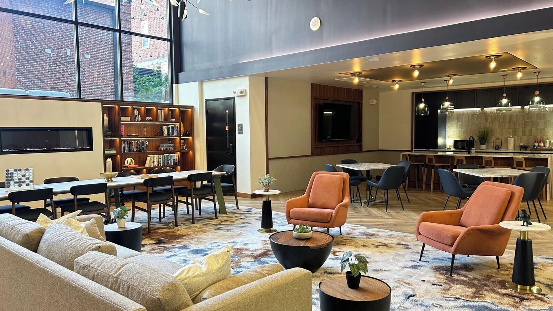 A spacious lounge area with a sofa set, a coffee table, a bookshelf, and a dining area with chairs and a table.