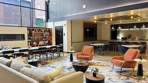 Ein großzügiger Lounge-Bereich mit einer Sofagarnitur, einem Couchtisch, einem Bücherregal und einem Essbereich mit Stühlen und Tisch.