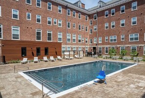 A swimming pool with lounge chairs and a wooden building adjacent to it. - Landing | Beautiful 1BD, Pool (West Hartford)