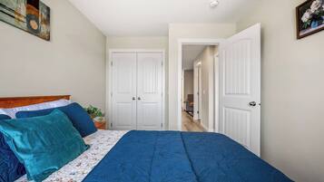 A bedroom with a bed, two doors, a hallway, and a plant.