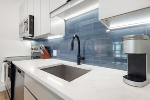 A modern kitchen with a stainless steel sink, a coffee machine, and a microwave. - Landing | Modern 1BD, Pool (West Hartford)