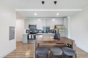 A modern kitchen with a central island, stainless steel appliances, and grey cabinetry. - Landing | Modern 1BD, Pool (West Hartford)