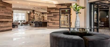 A modern lobby with a reception desk, seating area, and a decorative vase.