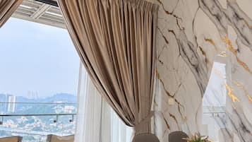 Ein moderner Essbereich mit einem Tisch für zwei Personen, Blick auf die Stadt durch große Fenster und einer Wand mit Marmormuster.