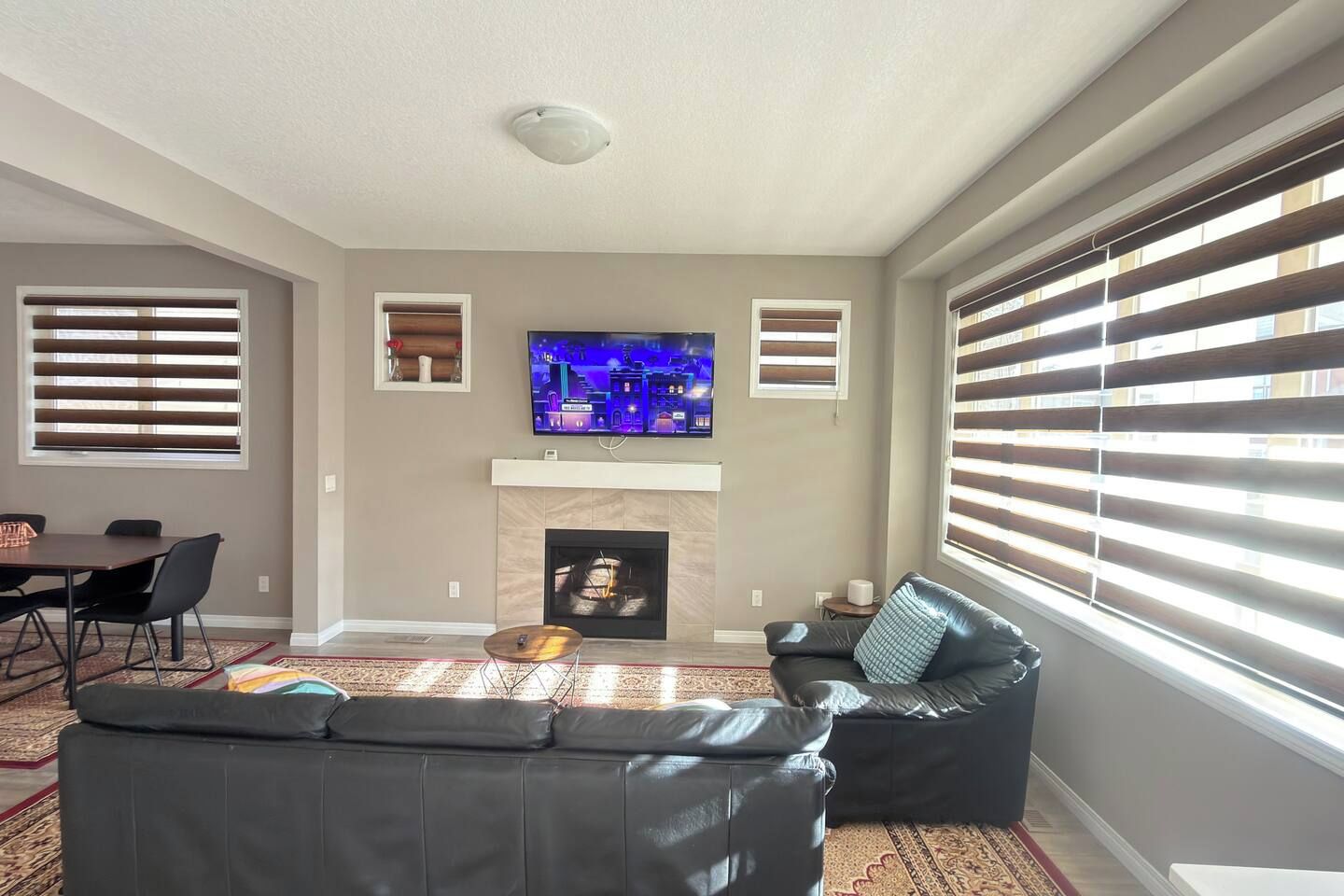 A living room with a fireplace, a flat-screen TV, a sofa, and a dining area.