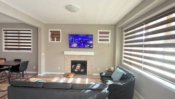 A living room with a fireplace, a flat-screen TV, a sofa, and a dining area.
