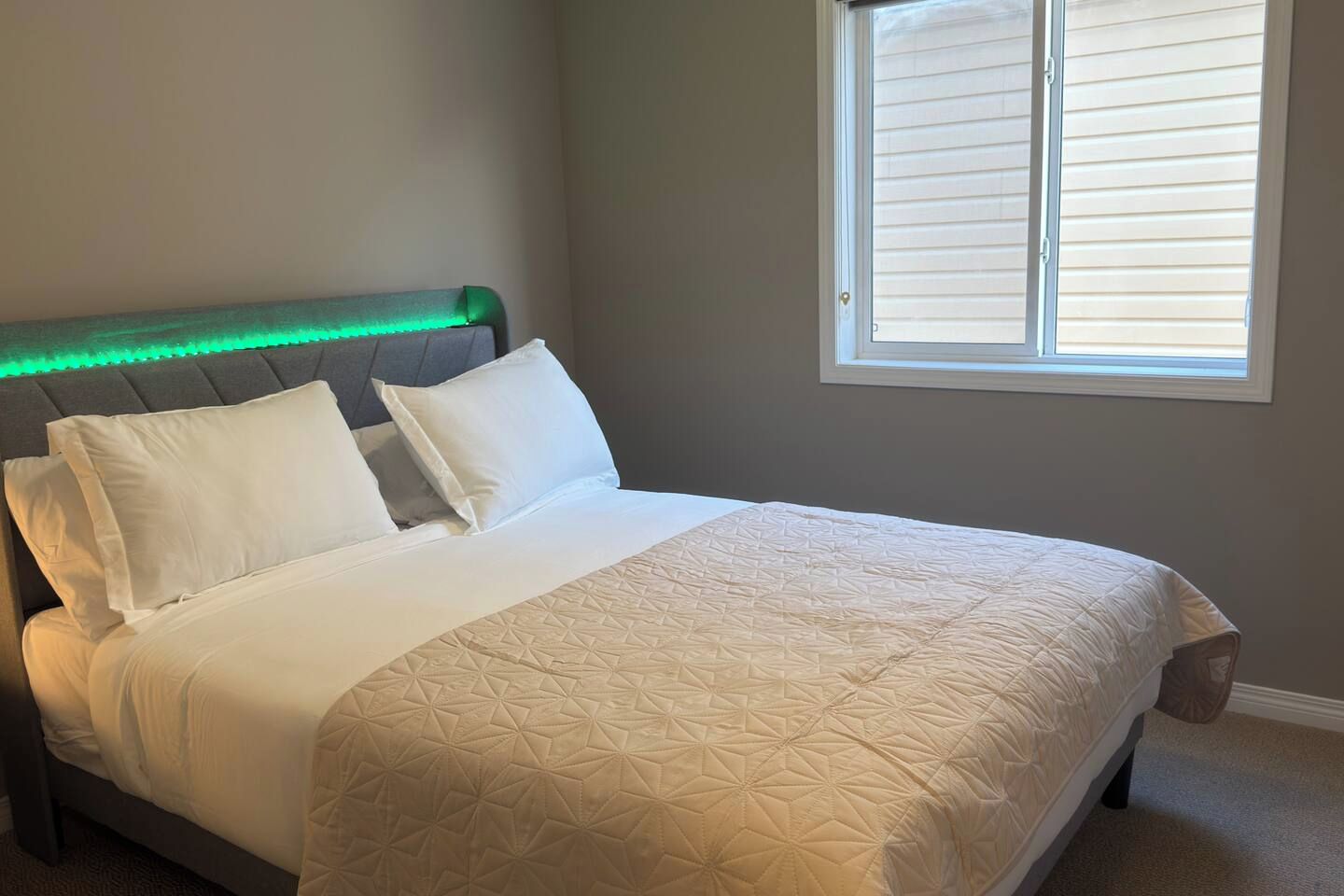 A bedroom with a bed, headboard, and a window.
