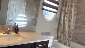 A bathroom with a sink, mirror, toilet, and bathtub.