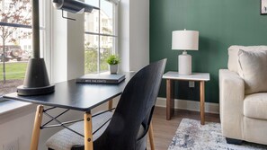 A room with a desk, chair, lamp, and a sofa. - Landing | Chic 1BD, Pool, Gym (Gainesville)