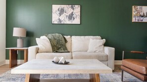 Uma sala de estar com sofá, mesa de centro, luminária e obras de arte na parede.