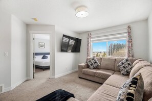 Un salon avec un canapé, un téléviseur, un lit dans la pièce adjacente et une fenêtre donnant sur un beau paysage.
