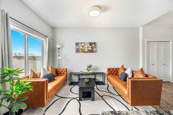 A modern living room with two leather sofas, a coffee table, and a painting on the wall.