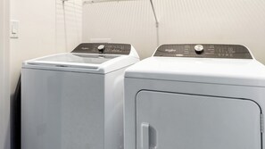 Two front-loading Whirlpool washers in a laundry room with a white wall and a vent. - Landing | Beautiful 2BD, Game Room, Gym (Gainesville)