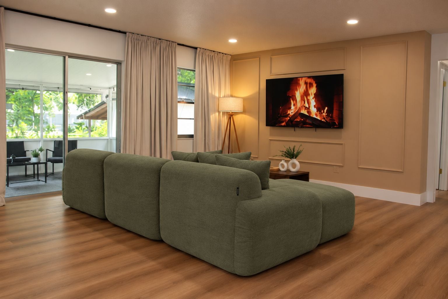 A modern living room with a sectional sofa, a flat-screen TV, and a floor lamp.