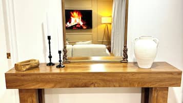 A wooden console table with a mirror, candles, and a vase.