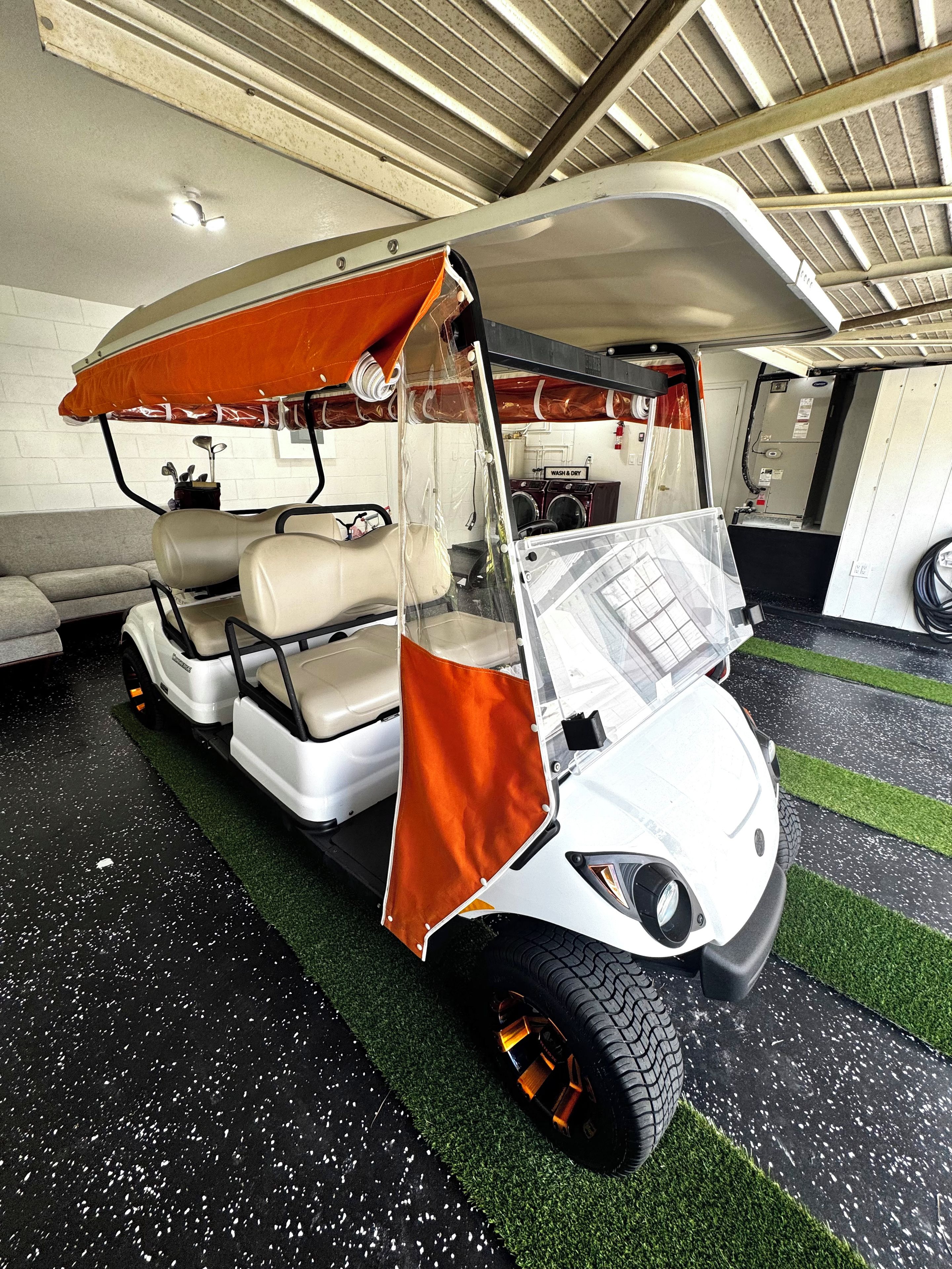 Un golf cart con una copertura trasparente, una lavatrice e un estintore sullo sfondo.