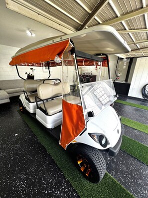 A golf cart with a transparent canopy, a washing machine, and a fire extinguisher in the background. - Golf Car Fun ,Spring & Swing Retreat (Altamonte Springs)