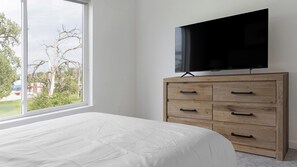 Una camera da letto con un letto, una cassettiera in legno e un televisore sopra.