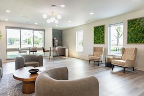A spacious living area with a modern kitchen in the background, large windows, and a ceiling with recessed lighting. - Landing | Chic 2BD, Gym (Council Bluffs)