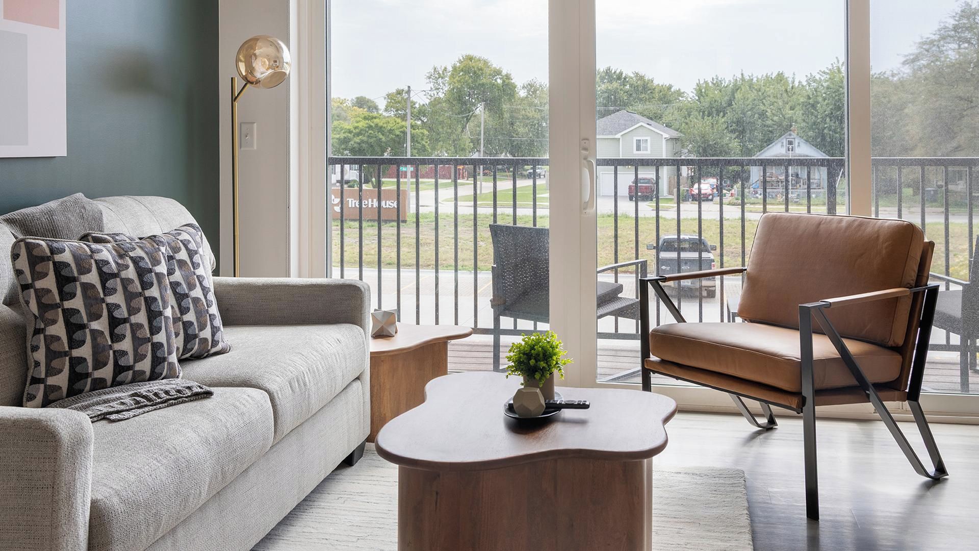 Un salon comprenant un canapé, un fauteuil, une table basse et donnant sur l’extérieur.