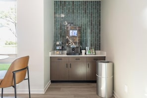 A compact kitchenette with a coffee machine, a trash can, and a chair. - Landing | Beautiful 1BD, Gym (Council Bluffs)