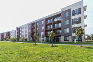 A modern multi-story residential building with balconies, a flat roof, and a sign advertising a lease. - Landing | Beautiful 1BD, Gym (Council Bluffs)