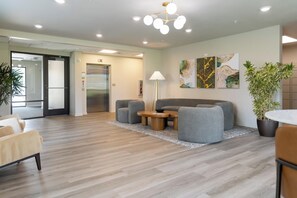 A modern lobby with a sofa, chairs, a coffee table, a lamp, and artwork on the wall.