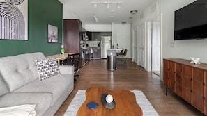 A modern living room with a sofa, coffee table, and a TV. - Landing | Stylish 1BD, Gym, Clubhouse (Jacksonville)