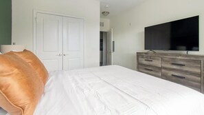 A bedroom with a bed, a wardrobe, a television, and a door leading to another room. - Landing | Stunning 1BD, Clubhouse, Gym (Jacksonville)