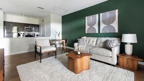 A modern living room with a sofa, coffee table, and a dining area with chairs and a table. - Landing | Stunning 1BD, Clubhouse, Gym (Jacksonville)