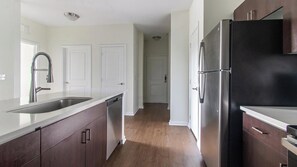 A modern kitchen with stainless steel appliances, a double sink, and wooden cabinets. - Landing | Stunning 1BD, Clubhouse, Gym (Jacksonville)