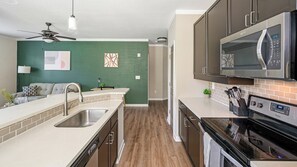 A modern kitchen with a microwave, oven, and dishwasher. - Landing | Stunning 2BD, Gym (Bluffton)