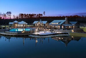 A resort with a large swimming pool, multiple guest buildings, and a dock. - Landing | Stunning 2BD, Gym (Bluffton)