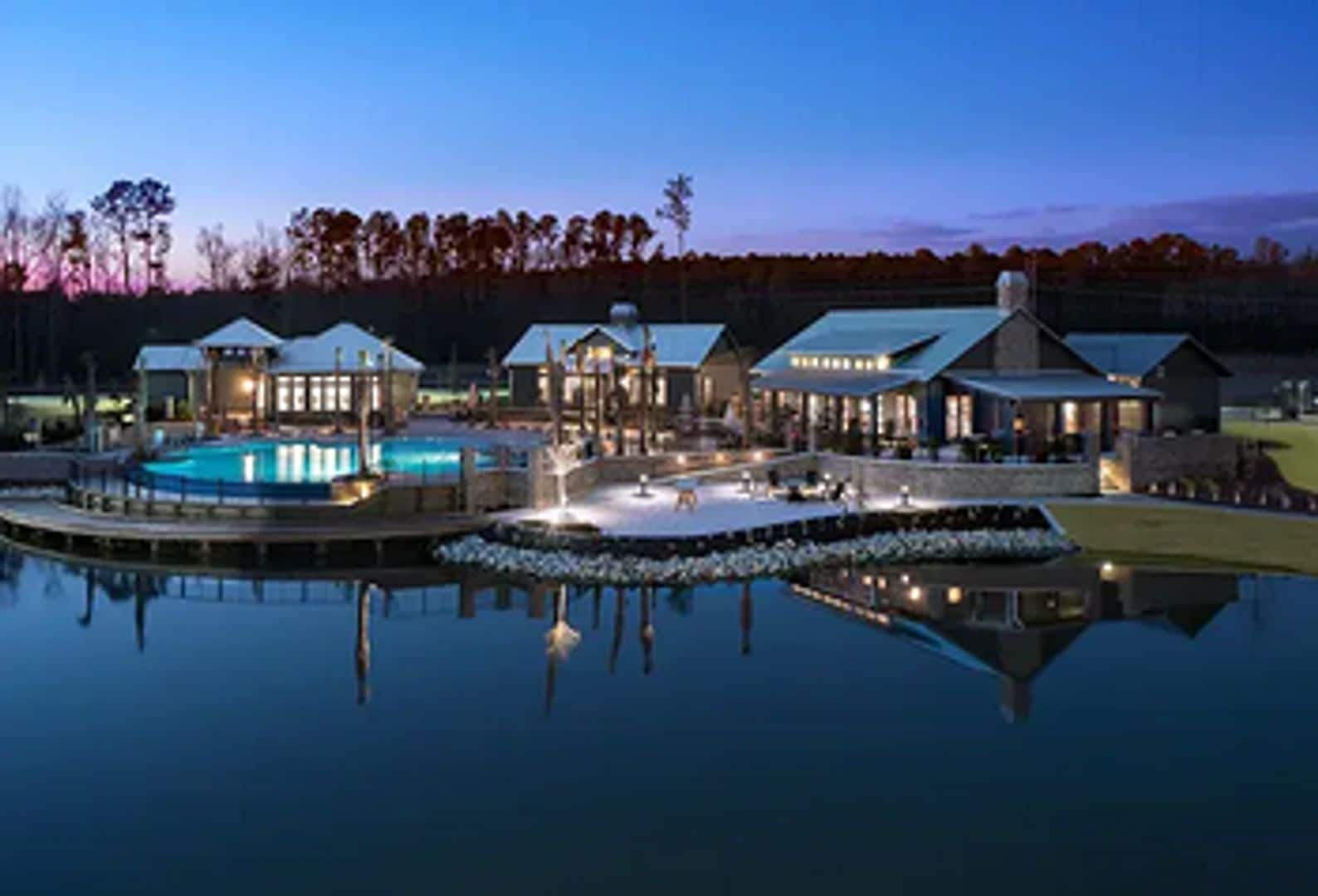 Ein Resort mit einem großen Schwimmbad, mehreren Gästegebäuden und einem Steg.