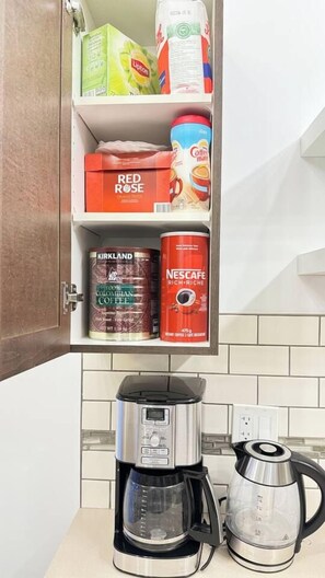 Cuina amb cafetera, búl i un armari amb productes de cafè.