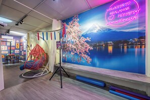 A room with a large wall mural of Mount Fuji, a hanging chair, and a neon sign.