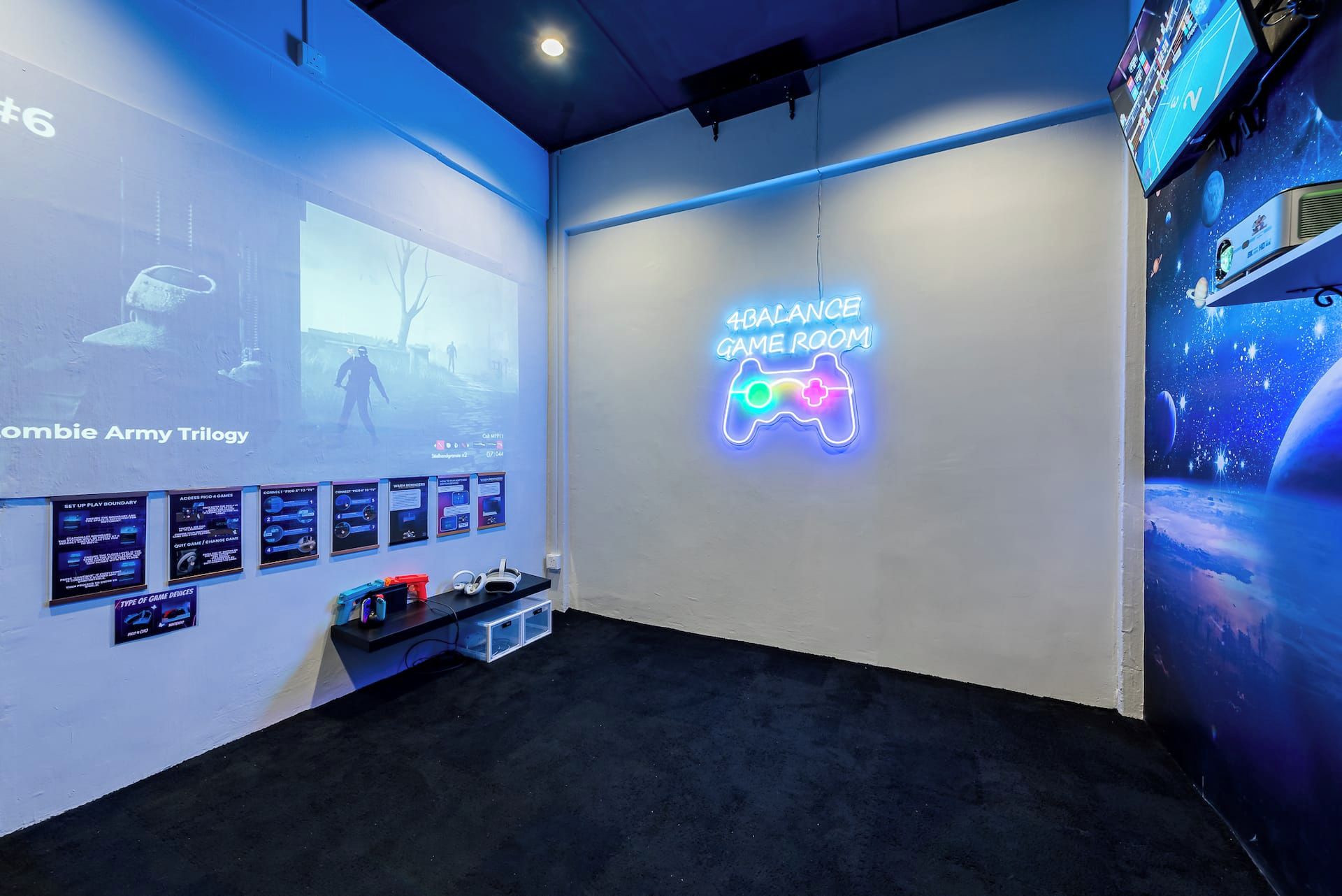 A gaming room with a neon sign, a large screen displaying a game, and a shelf with gaming accessories.