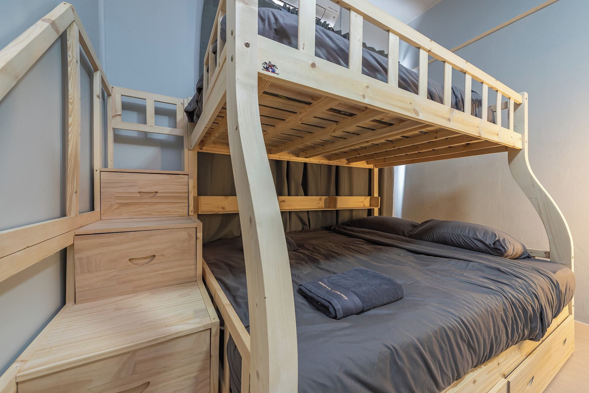A bunk bed with a wooden frame, a desk with drawers, and a window.