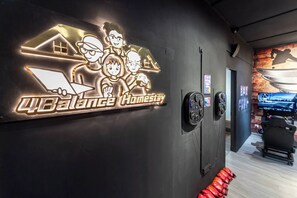 A wall with a neon sign reading '4Balance Homestay' and a row of red boxing gloves on the floor.
