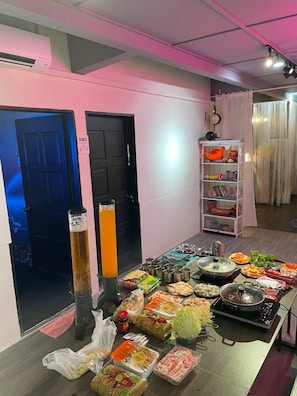 A room with a dining table set with various food items and a beverage dispenser.
