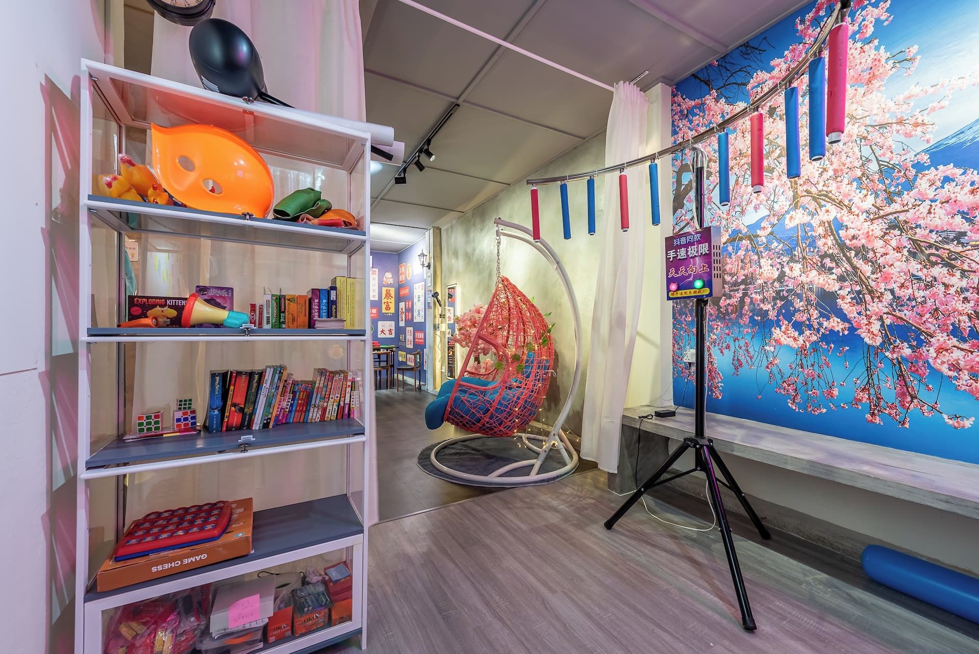 A room with a bookshelf, a hanging chair, and a wall with a cherry blossom mural.