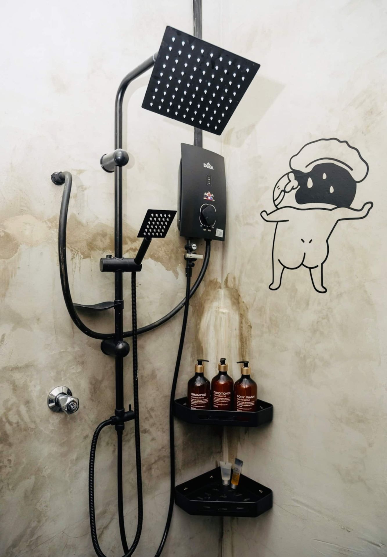 A shower with a handheld showerhead, a wall-mounted rain showerhead, and a control panel. There are also three bottles of shampoo, conditioner, and body wash on a shelf.