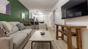 A modern living room with a sofa, a coffee table, and a TV. - Landing | Chic 1BD, Gym (Bridgeport)