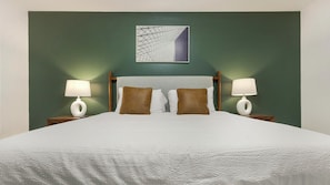 A hotel room with a large bed, two bedside lamps, a headboard, and a wall-mounted artwork. - Landing | Beautiful 2BD, Gym (Bridgeport)