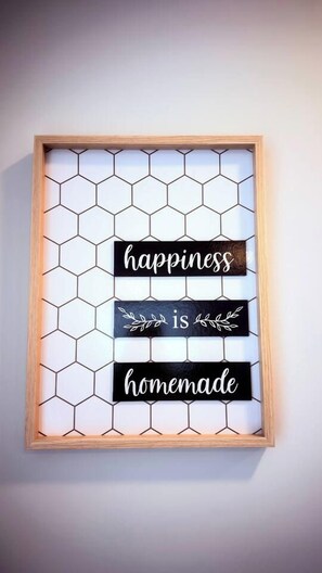 A framed sign with a honeycomb pattern and text stating 'happiness is homemade.' - Savanna Breeze | Modern 3BR | Near YYC Airport (Calgary)