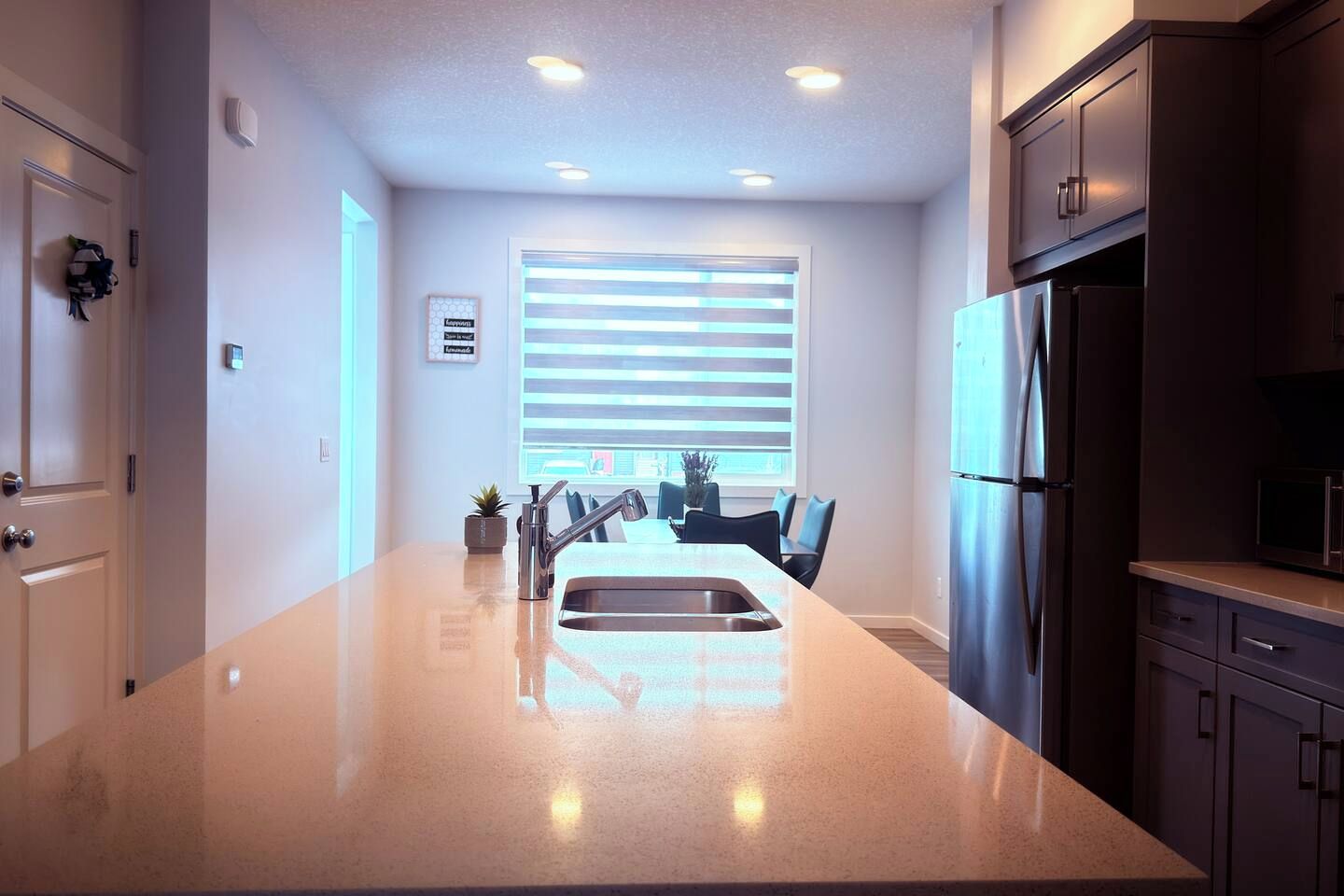 A modern kitchen with a central island, stainless steel appliances, and a dining area with chairs.