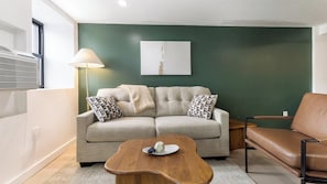 Ein Wohnzimmer mit einer Couch, einem Couchtisch, einer Lampe und einem Sessel.