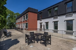 A courtyard with outdoor seating and a building with a brick facade and large windows. - Landing | Amazing 2BD, Gym (Bridgeport)